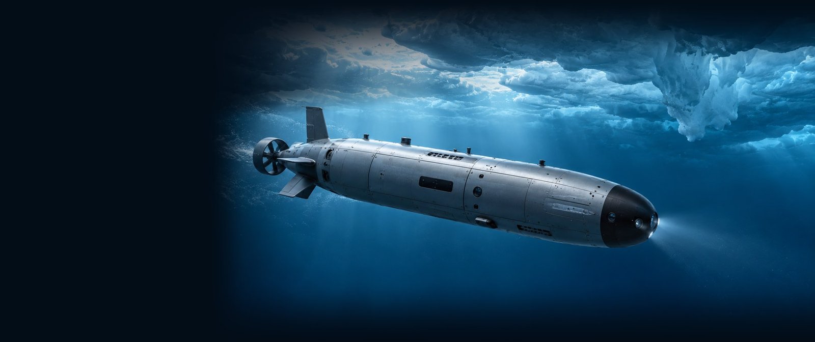 The vehicle under way beneath an ice ceiling, forward light on, open water ahead.